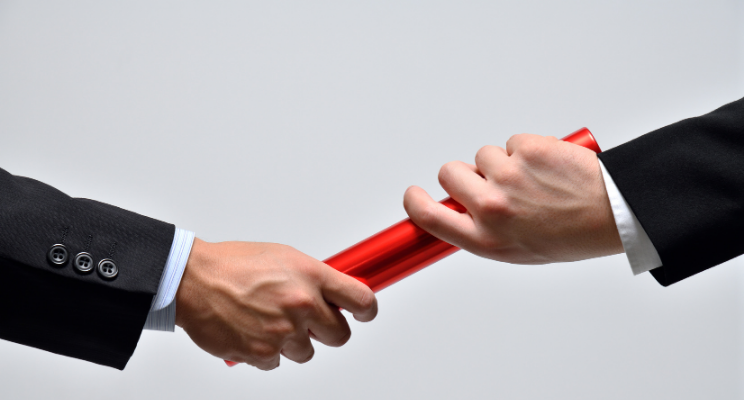 Men in business suits handing off a red baton to each other.